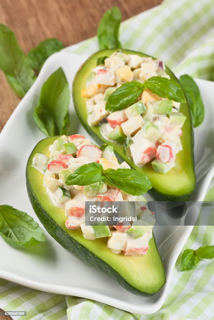 Avocado salad Avocado stuffed with crab, cucumber, egg, red onion and sauce mayonnaise on white plate Avocado Stock Photo