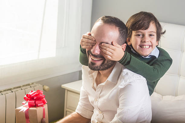 istock Son holding eyes of father with gift 628563212
