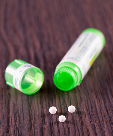 Homeopathic pills over wooden table, vertical image
