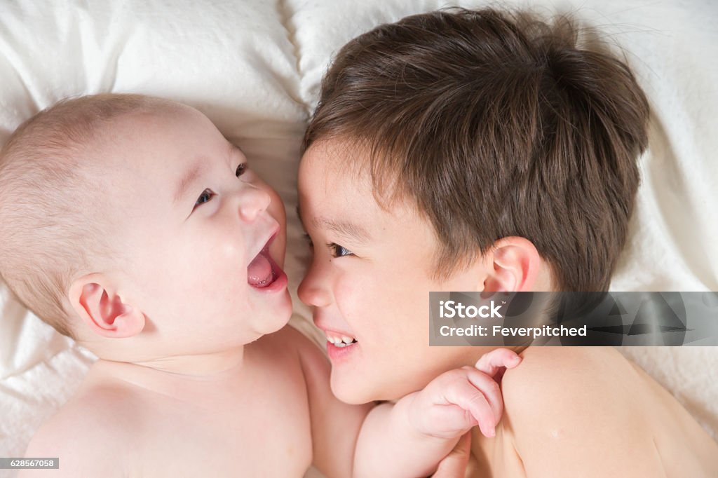 Mixed Race Chinese and Caucasian Baby Brothers Having Fun Laying Young Mixed Race Chinese and Caucasian Baby Brothers Having Fun Laying In Bed. Affectionate Stock Photo