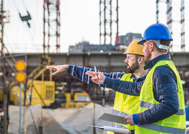 Successful people working on common project Engineers and contractors on construction site, following the progess of bridge and road infrastructure development. Two experts on construction platform in reflective wear with hardhats discussing project phases and successful previous developments. Image taken with Nikon D800 and 85mm lens, developed from RAW in XXXL size. Location: Central Europe, Europe tower crane stock pictures, royalty-free photos & images