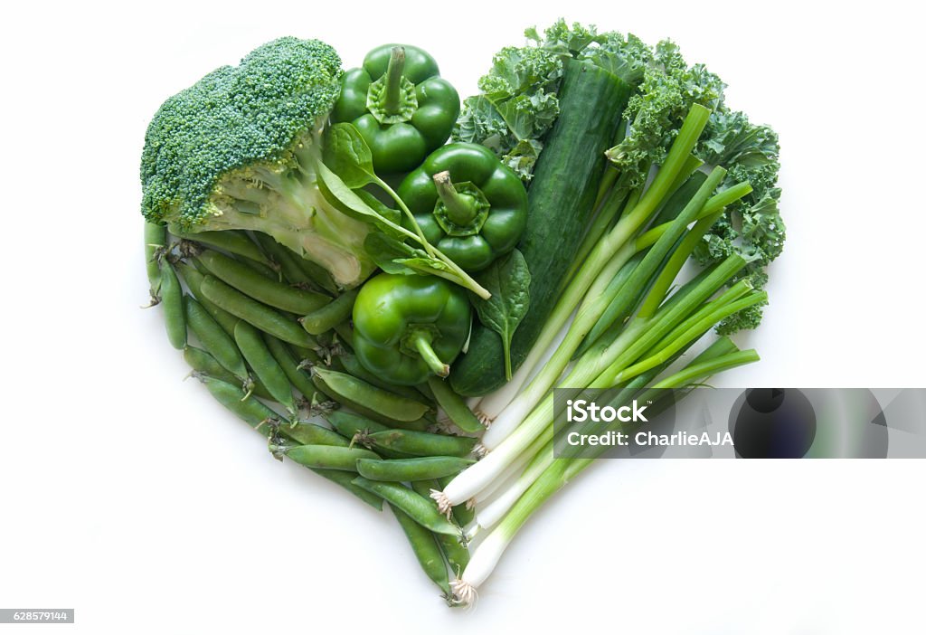 Heart shape green vegetables Selection of green vegetables and leaves including kale and broccoli in the shape of a heart over a whtie background Vegetable Stock Photo