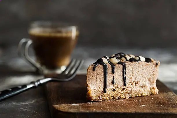 Photo of Raw chocolate mousse cake with  hazelnuts, coffee. Grey background