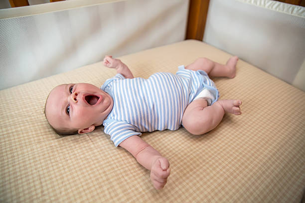 Baby Boy Laying in Crib Yawning stock photo