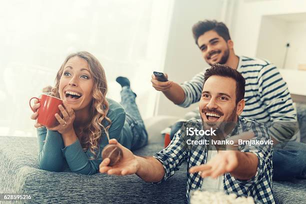 Grupo De Amigos Viendo Televisión En Su Hogar Foto de stock y más banco de imágenes de Televisión - Televisión, Amistad, Personas