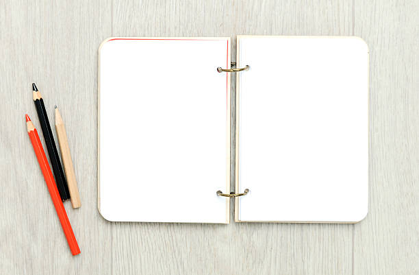 istock Opened blank notepad with colorful pencils on wooden table 628595408