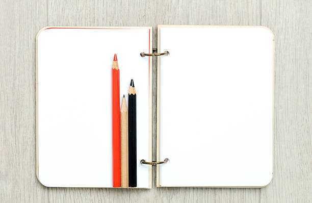 istock Opened blank notepad with colorful pencils on wooden table 628595500