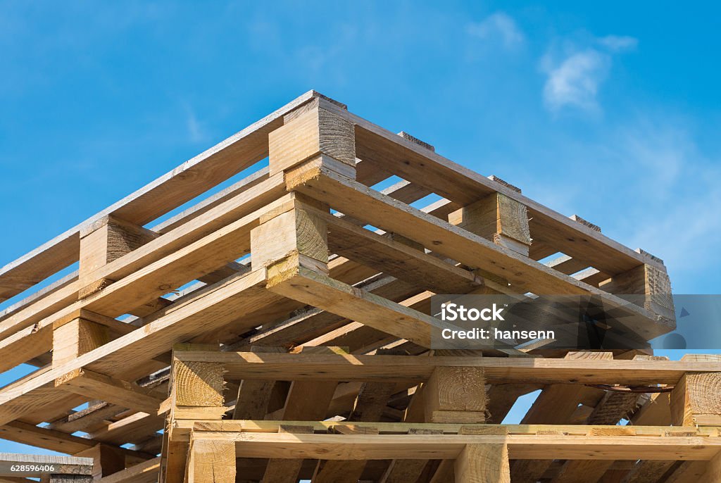 piled up pallets stacked up pallets against a blue sky Pallet - Industrial Equipment Stock Photo