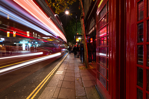 Motion blur of a London red double decker bus passing an iconic red phone box. Still from time lapse video ID 542885408.