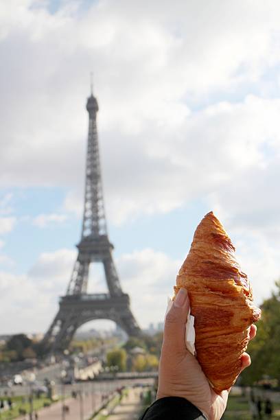 istock hand holding croissant at Eiffel tower in Paris 628603782