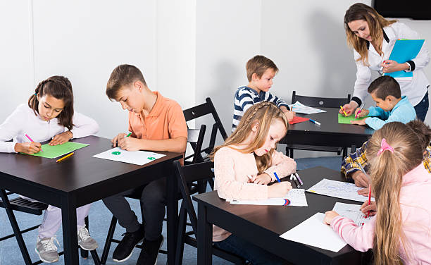 petits enfants attentifs avec un dessin d’enseignant en classe - report card number 8 school education photos et images de collection