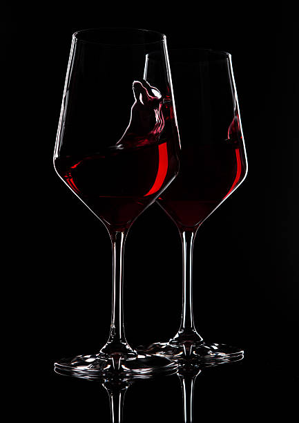 istock Glasses of red wine with reflection on black 628612378