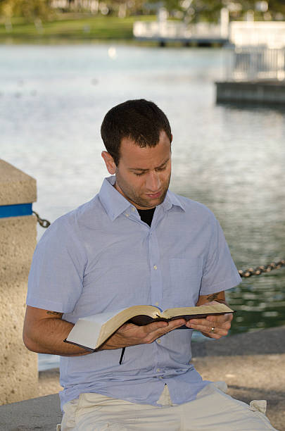 istock Man reading the Bible at the lake. 628616384
