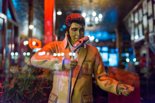 Memphis, United States - May 17, 2016: A small business on Beale Street displays an Elvis statue in it's retail window display. Lights are reflected in the glass. 