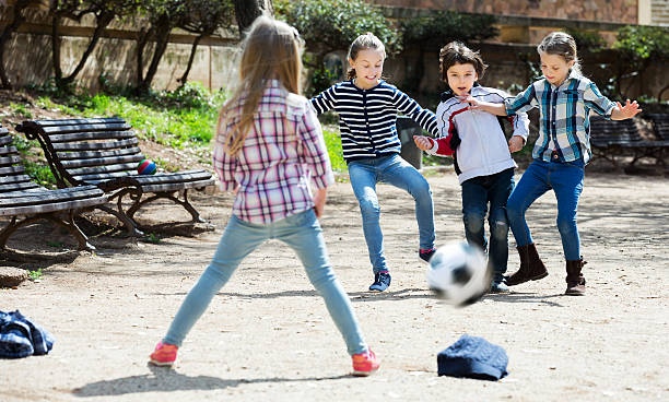enfants jouant dans la rue de football - foot walk photos et images de collection