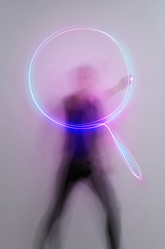 man in aktion drawing light trail symbols with laserpointer, time exposure, search icon, magnifier