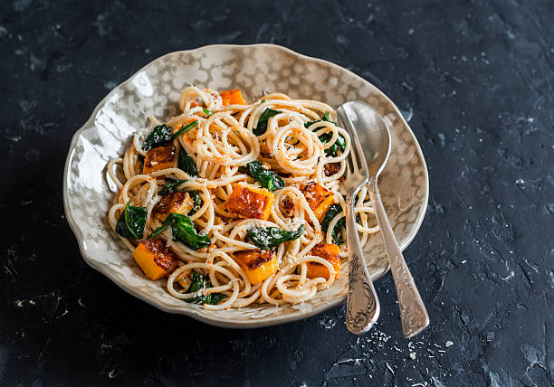 istock Baked pumpkin and spinach spaghetti on wooden dark table 628651028