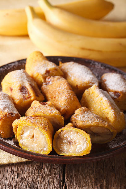 istock Fried bananas sprinkled with powdered sugar close-up. Vertical 628659184