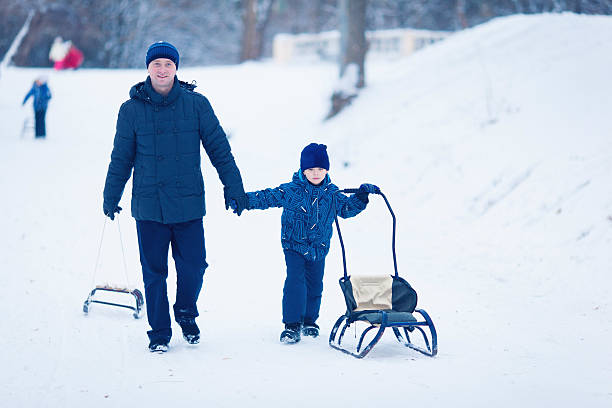 istock Young Family Running Through Snow With Sled 628663104