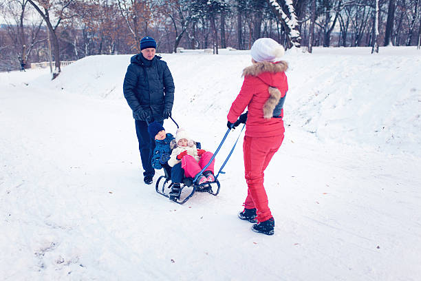 istock Young Family Running Through Snow With Sled 628663222