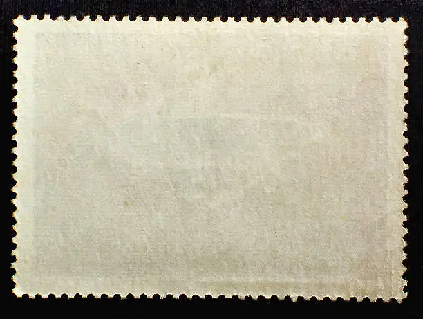Old blank posted stamp isolated on black background