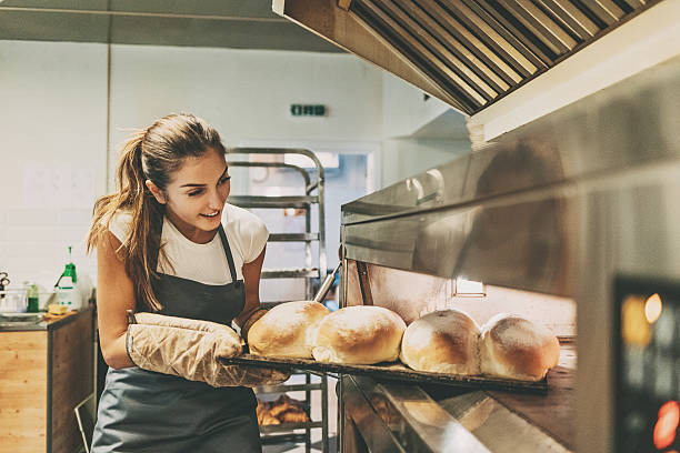 fornaio tirando un vassoio con pane caldo - baking baker bakery bread foto e immagini stock