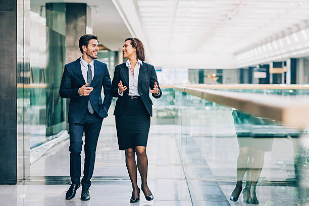 Formal business style Two business persons walking and talking inside of office building, with copy space. woman necktie stock pictures, royalty-free photos & images