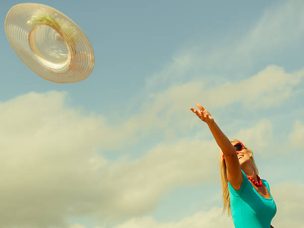 istock girl trowing hat up on beach 628695558