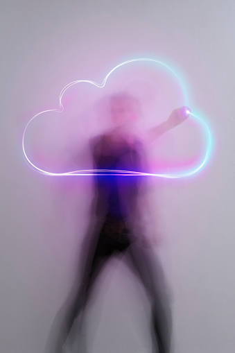 man in aktion drawing light trail symbols with laserpointer, time exposure, cloud icon