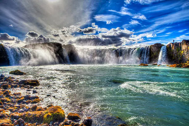 People admiring Godafoss waterfall and the solar halo, north of Iceland.