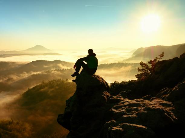 istock Man sit on exposed rock. Viewpoint with heather and branches 628711434