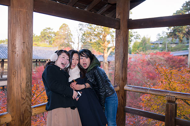 istock Three women playing together in Japanese fall foliage 628729550