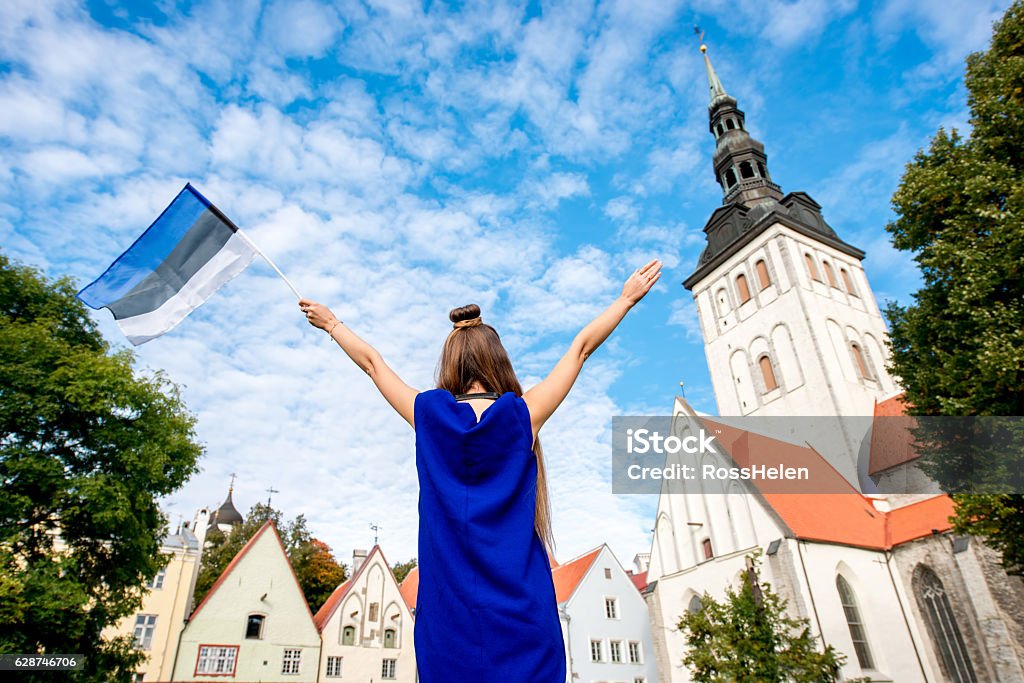 Woman traveling in Tallinn Young female tourist with estonian flag in front of saint Nicholas church in the old town of Tallinn. Woman having great vacations in Estonia Adult Stock Photo