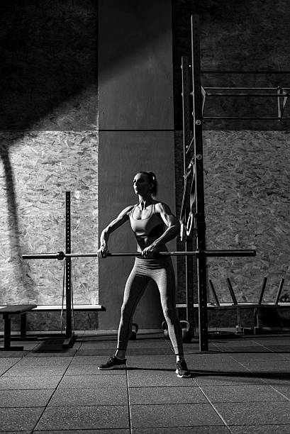 istock Young slim woman exercising with a long metal bar 628746842