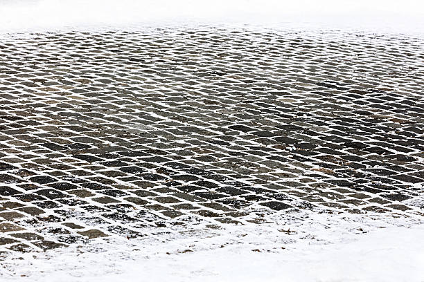 gray granite cobblestone city sidewalk covered with white snow
