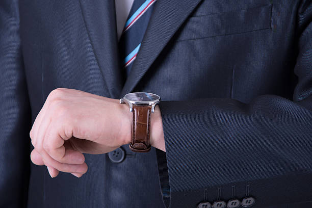 Businessman looking at the time on his watch Businessman looking at the time on his watch river wear stock pictures, royalty-free photos & images