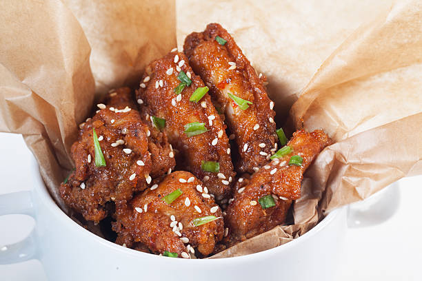 baked chicken wings in kraft paper closeup with green onion stock photo