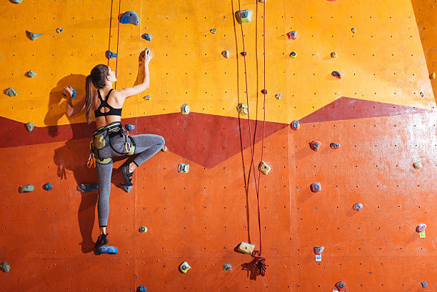 attractive woman climbing up the wall in gym - recreational sports imagens e fotografias de stock