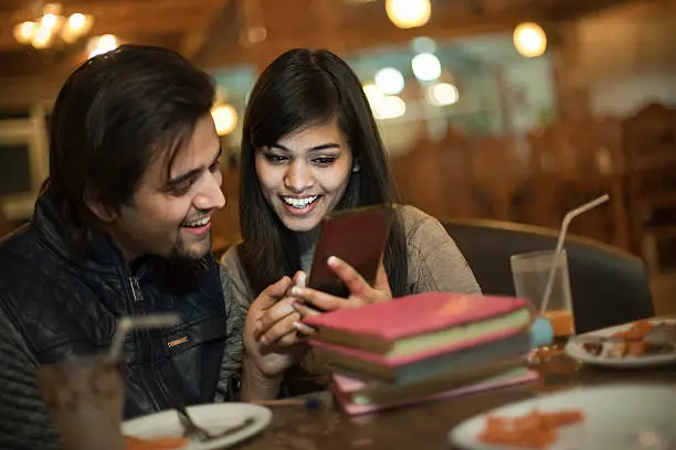 Photo of College student friends learning and teaching together in a restaurant.