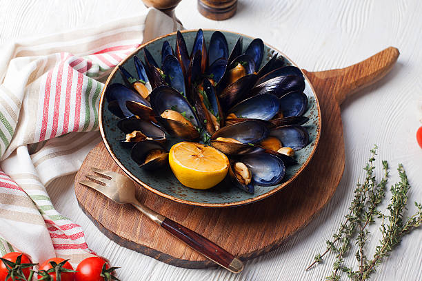 mussels in a bowl on  wooden board, lemon stock photo