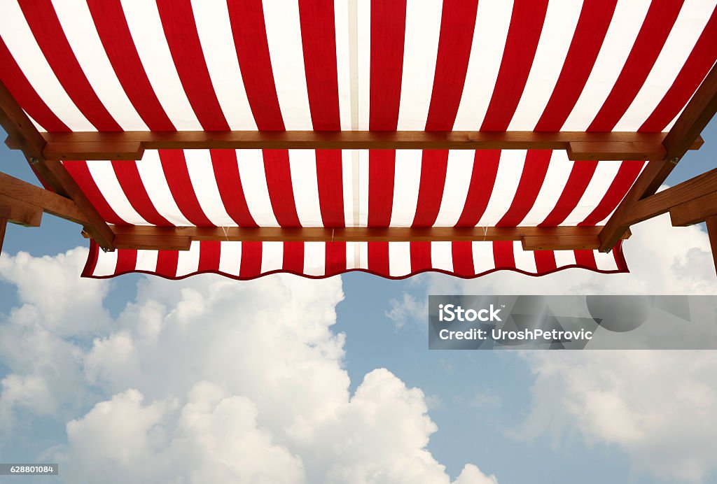 View from shade below red white striped awning This is a view from space under red white striped awning. Awning Stock Photo