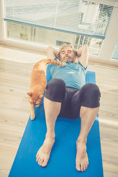 istock Senior Man exercising at Home with his Ginger Cat 628802646