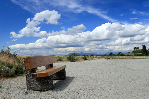 An outdoor bench at  Garry point park, Richmond BC, Canada on a sunny afternoon with brilliant clouds on the background