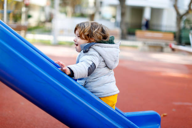 Toddler active boy having fun on playground , Happy laughing Baby boy is climbing up the slide