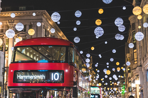 Red double decker bus in London during Christmas time. Lights and decorations over the famous London street reflecting on the bus surface. Travel and tourism concpets