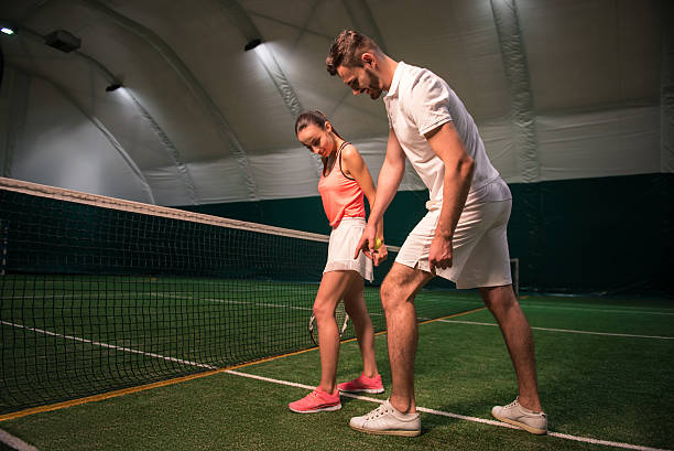istock Professional instructror teaching young woman to play tennis 628818924