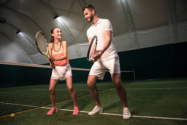 istock Positive instructor showing smiling woman how to hold racket 628819140