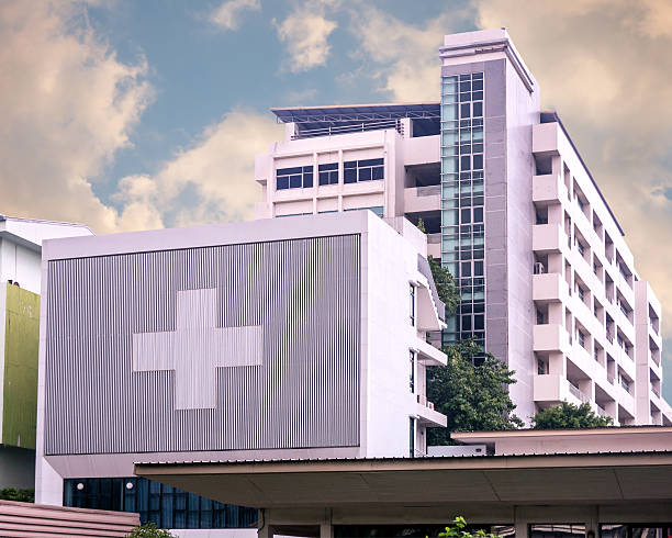 bangunan rumah sakit dengan simbolis besar pada hari berawan - hospital building potret stok, foto, & gambar bebas royalti