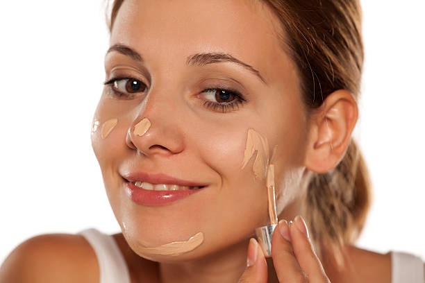 istock young beautiful woman applying foundation on her face 628835442