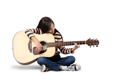 Young asian girl with a accoustic guitar, Isolated on grey background
